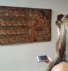 Image of person at artwork with the artwork in the mobile phone